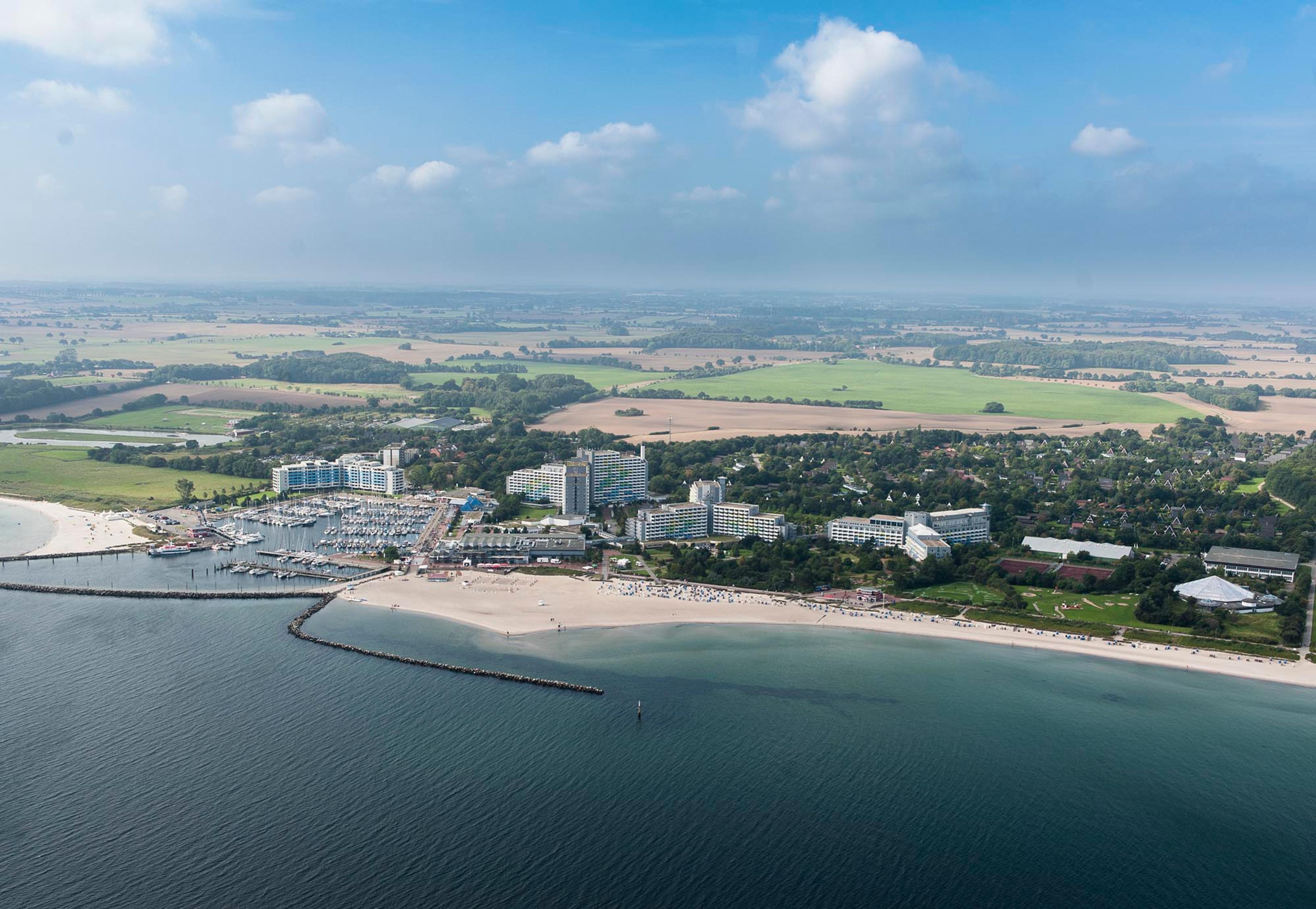 Luftaufnahme einer Küstenstadt an der Ostsee mit Strand, Hafen und umliegenden Feldern