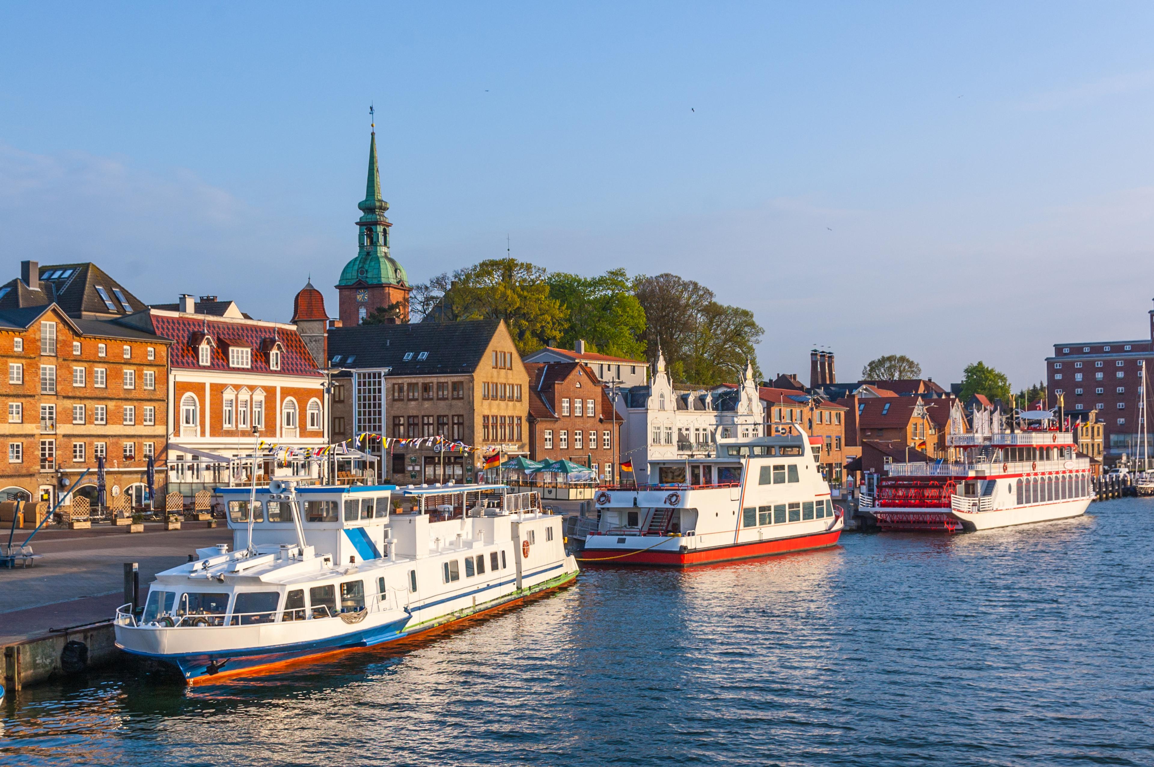 Hafenstadt mit historischen Gebäuden und mehreren Passagierschiffen am Wasser