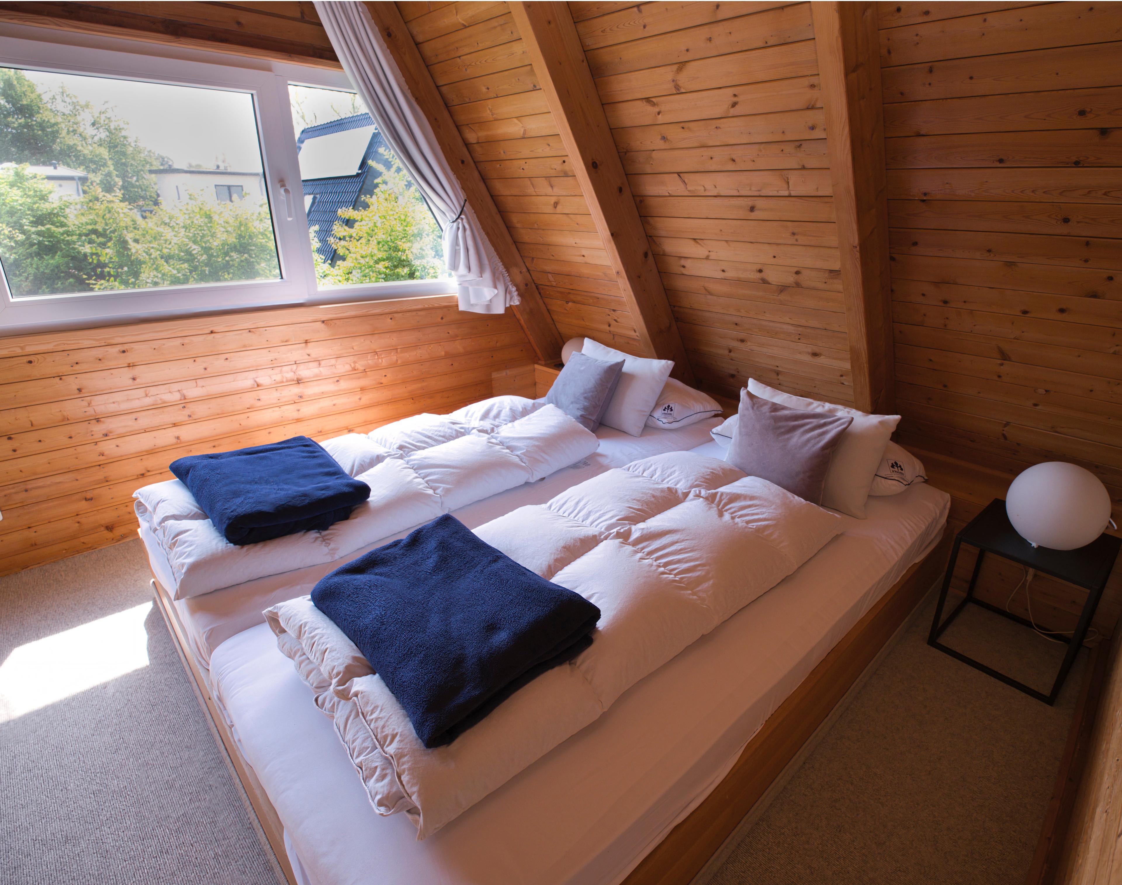 Ein gemütliches Schlafzimmer mit Holzverkleidung, einem Doppelbett und einem Fenster mit Blick ins Grüne