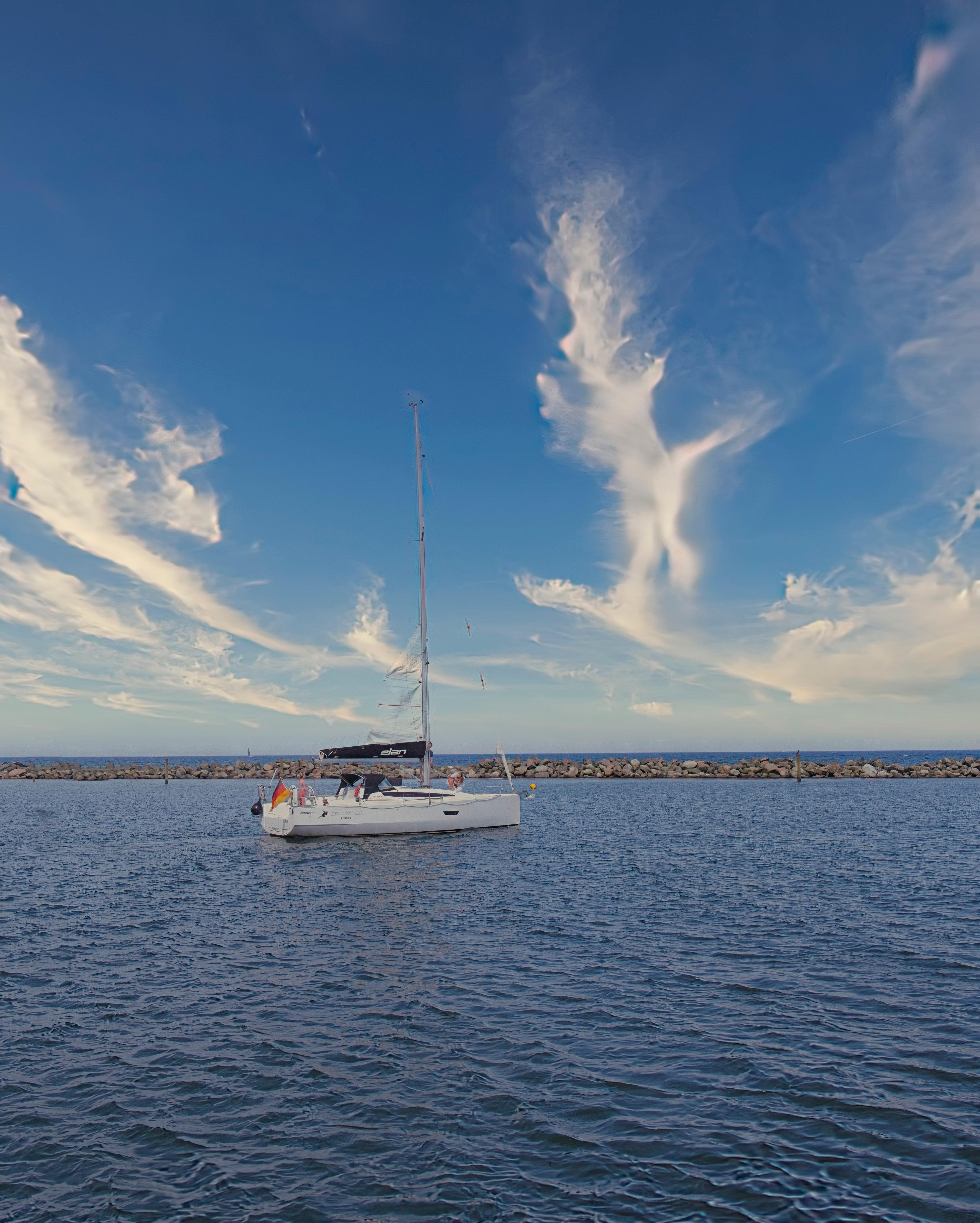 Ein weißes Segelboot auf dem offenen Meer mit einem dramatischen Himmel voller Wolken