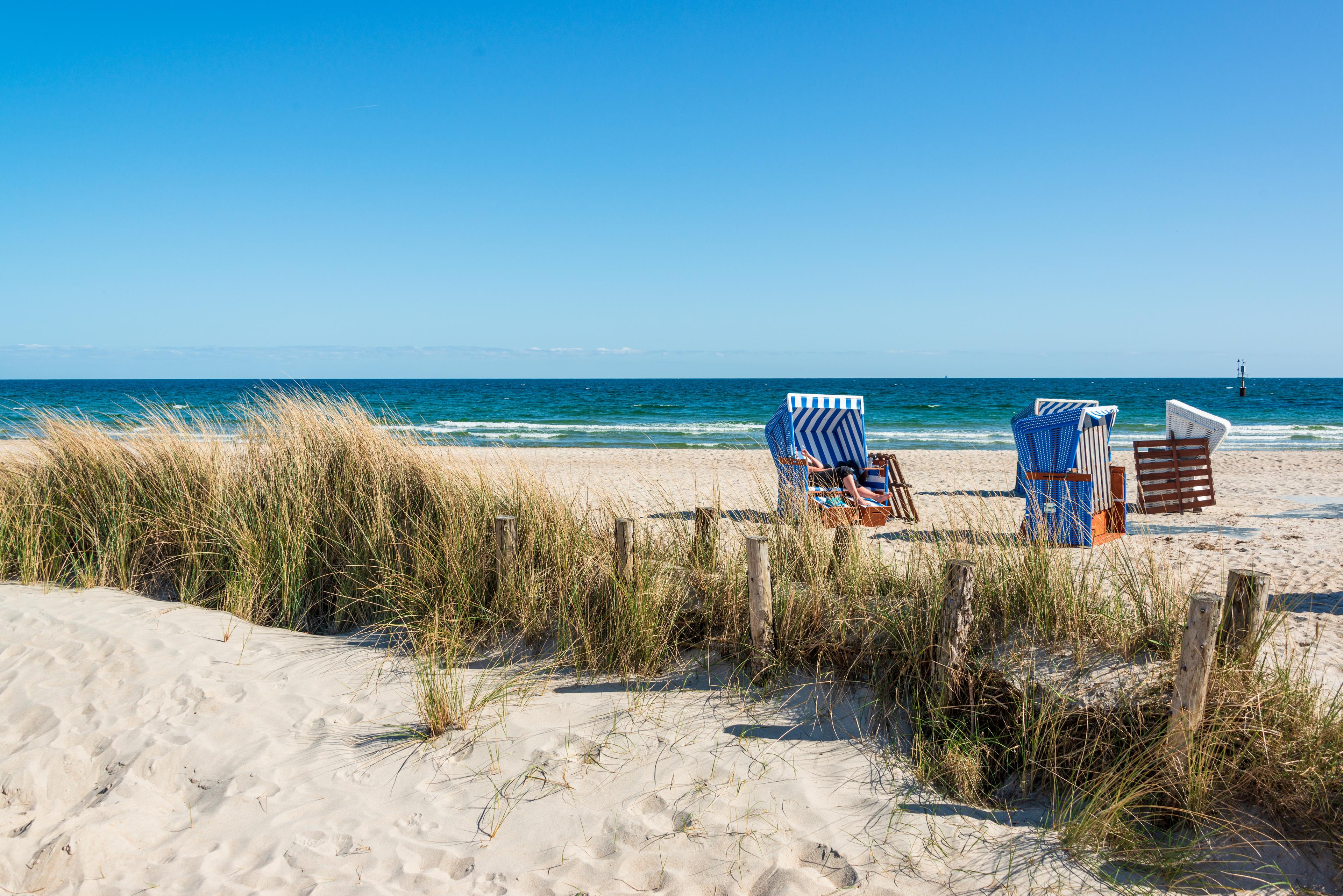 Ein Strandkorb auf einem Sandstrand mit Blick auf das Meer und blauen Himmel