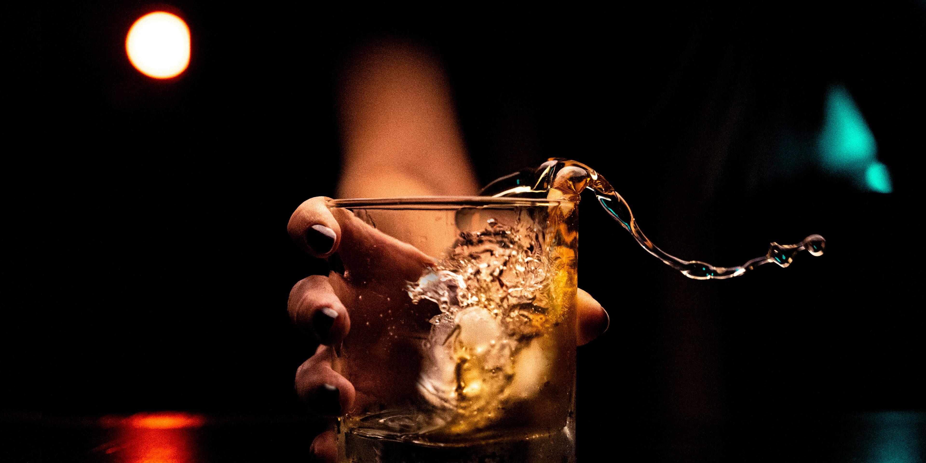 A person holding a glass with a liquid inside