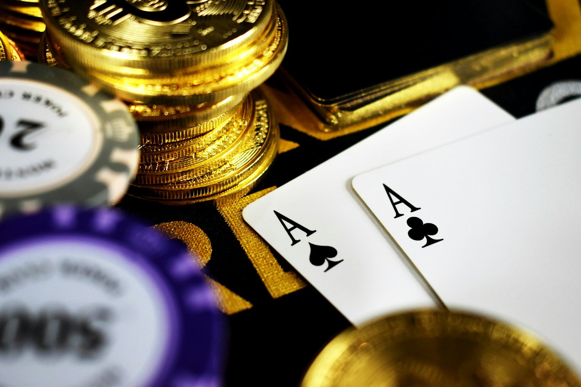 Close-up of poker chips, playing cards, and gold coins on a gaming table