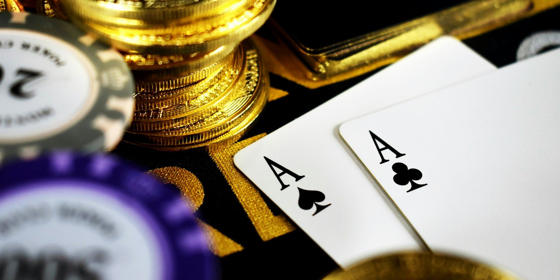 Close-up of poker chips, playing cards, and gold coins on a gaming table