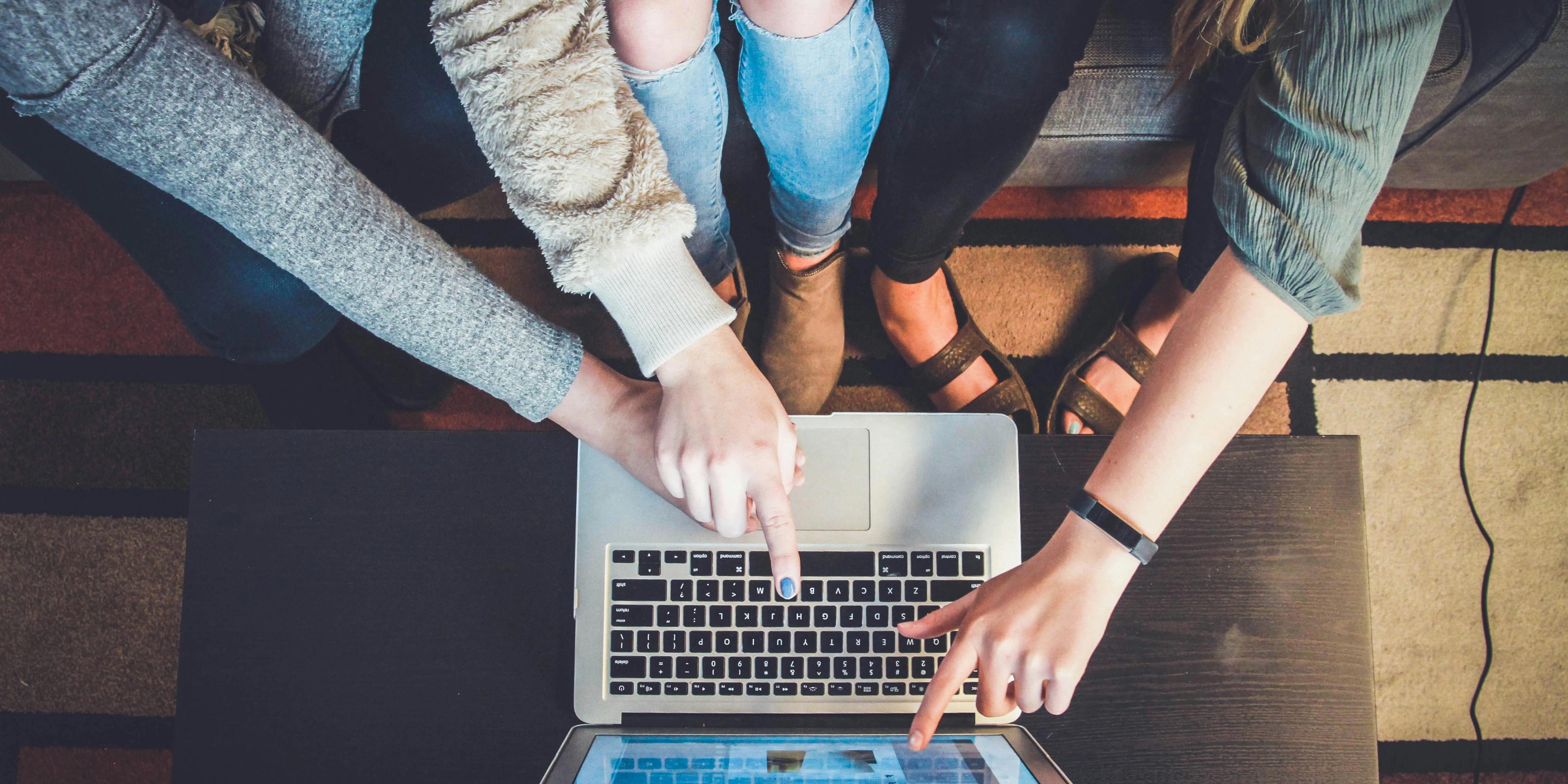 A group of person pointing on a laptop