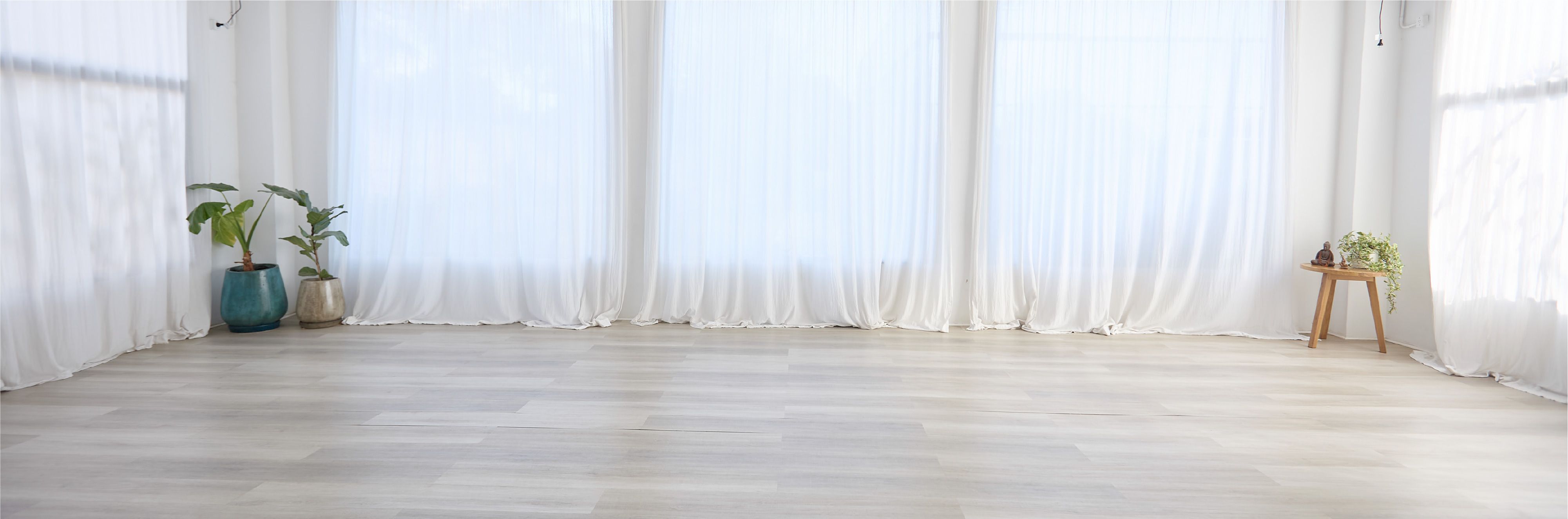 Salón de yoga luminoso con cortinas blancas en Espacio Raíz