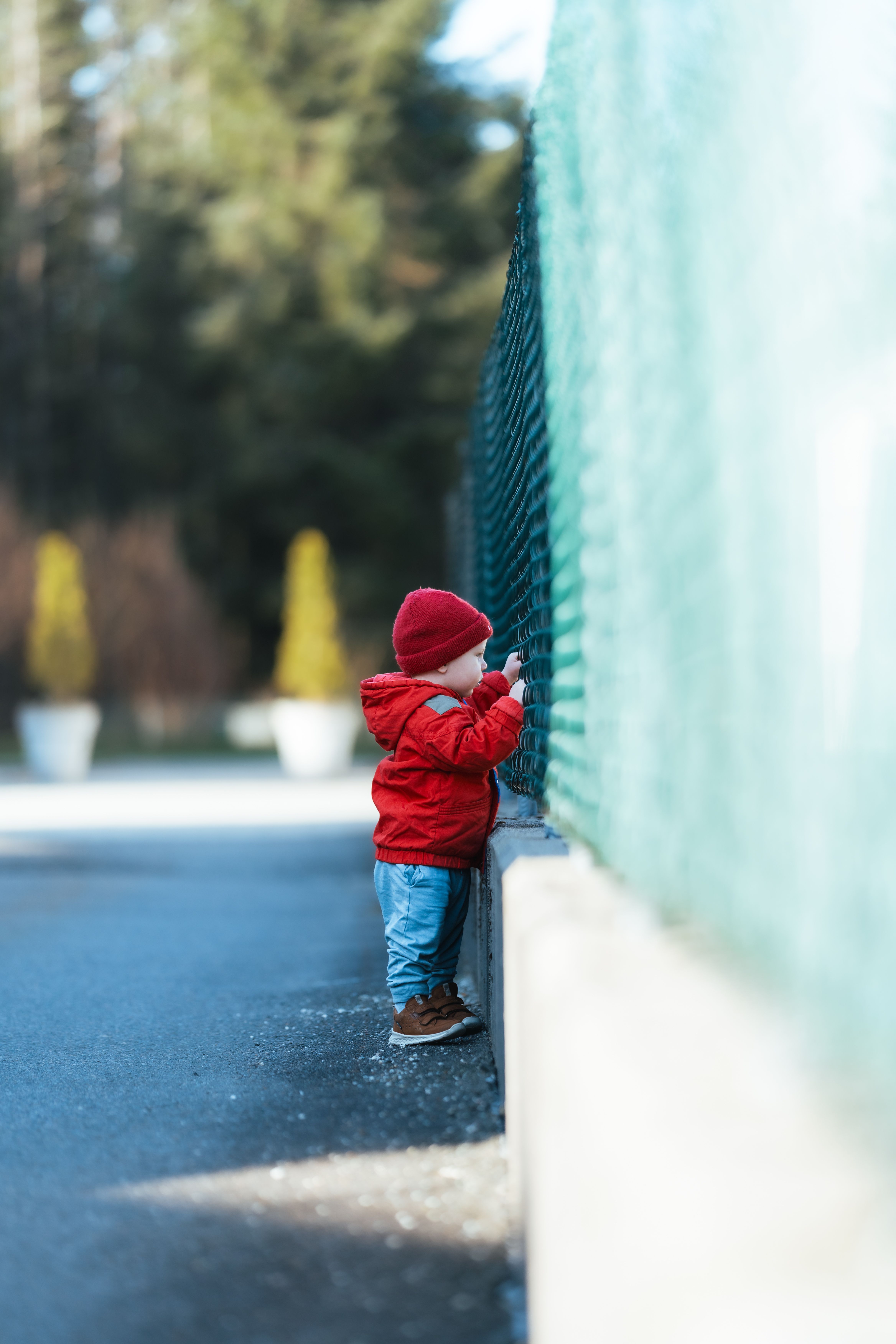 Liten gutt holder i et gjerde og ser ut