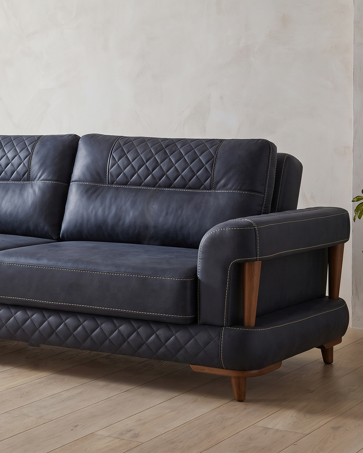 Aurigo sofa, jedan kraj snimljen u prostoriji: prošiveni pojas naslona, glatko sedište i rukonaslon nad otvorom sa stubovima