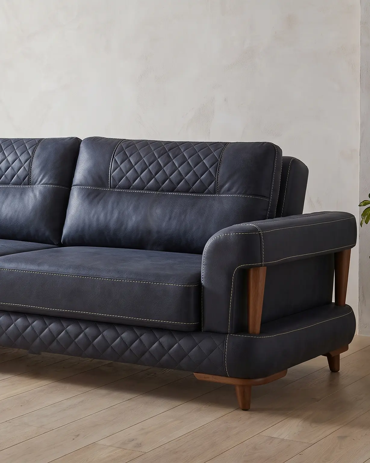 Aurigo sofa, jedan kraj snimljen u prostoriji: prošiveni pojas naslona, glatko sedište i rukonaslon nad otvorom sa stubovima