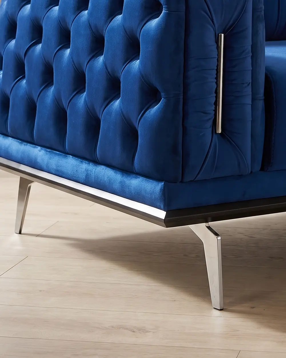 Paularo sofa, pogled pod telo: tamna traka oštrih ivica, svetla metalna šina uz nju i noga u obliku sečiva nasađena na šinu