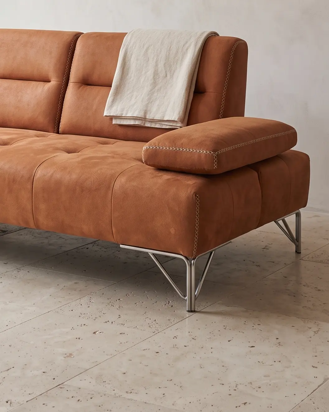 Ortisei sofa, desni kraj: jastuk rukonaslona leži ravno na platformi, svetao krstasti prošiv po ivici i nogara od savijene metalne cevi