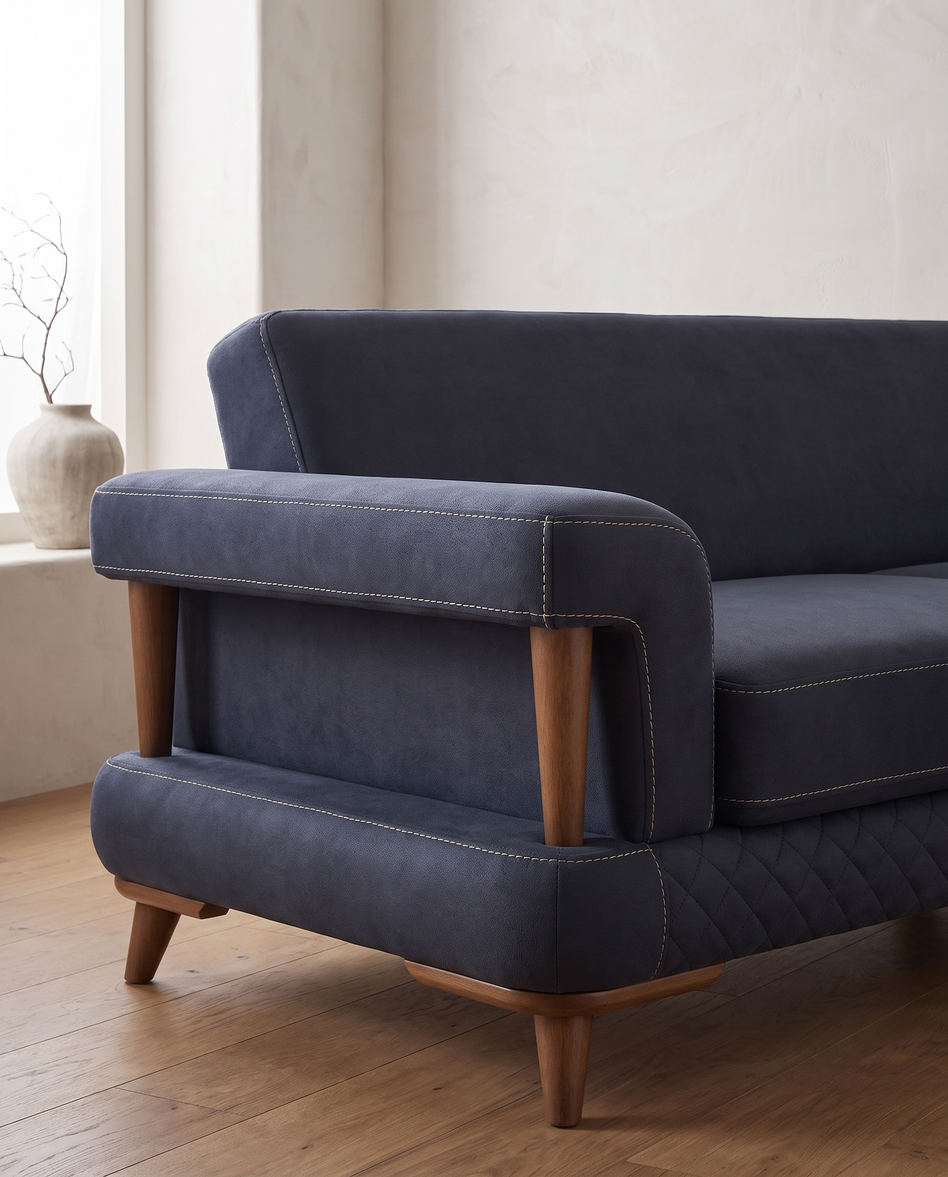 Aurigo sofa, krupni plan jednog kraja: dva drvena stuba drže rukonaslon, pregrada u istoj tkanini zatvara otvor, a drvena letvica obilazi ugao pod postoljem