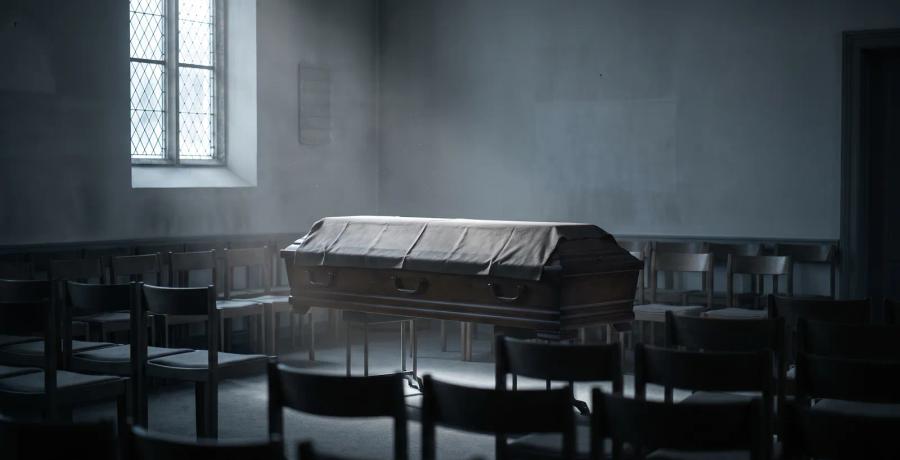 A single closed casket in an empty funeral chapel, representing cremation or burial without family authorization.