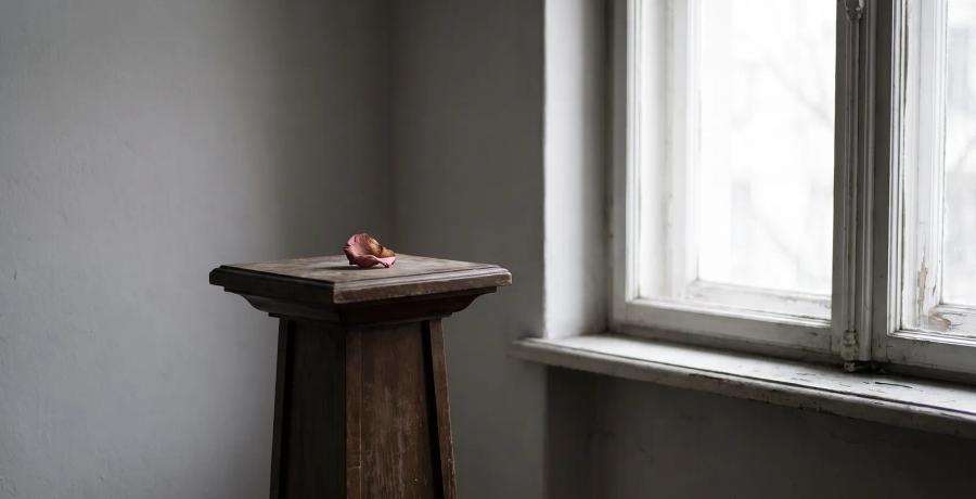 An empty memorial display stand beside a window, symbolizing a funeral home losing a loved one's body or ashes.