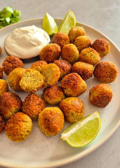 Ein rustikaler Teller mit knusprigen Falafel mit Limetten-Wedges.