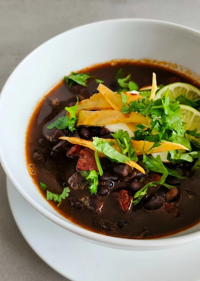 Schwarze Bohnensuppe aus Mittelamerika mit frischem Koriander und Totopos.