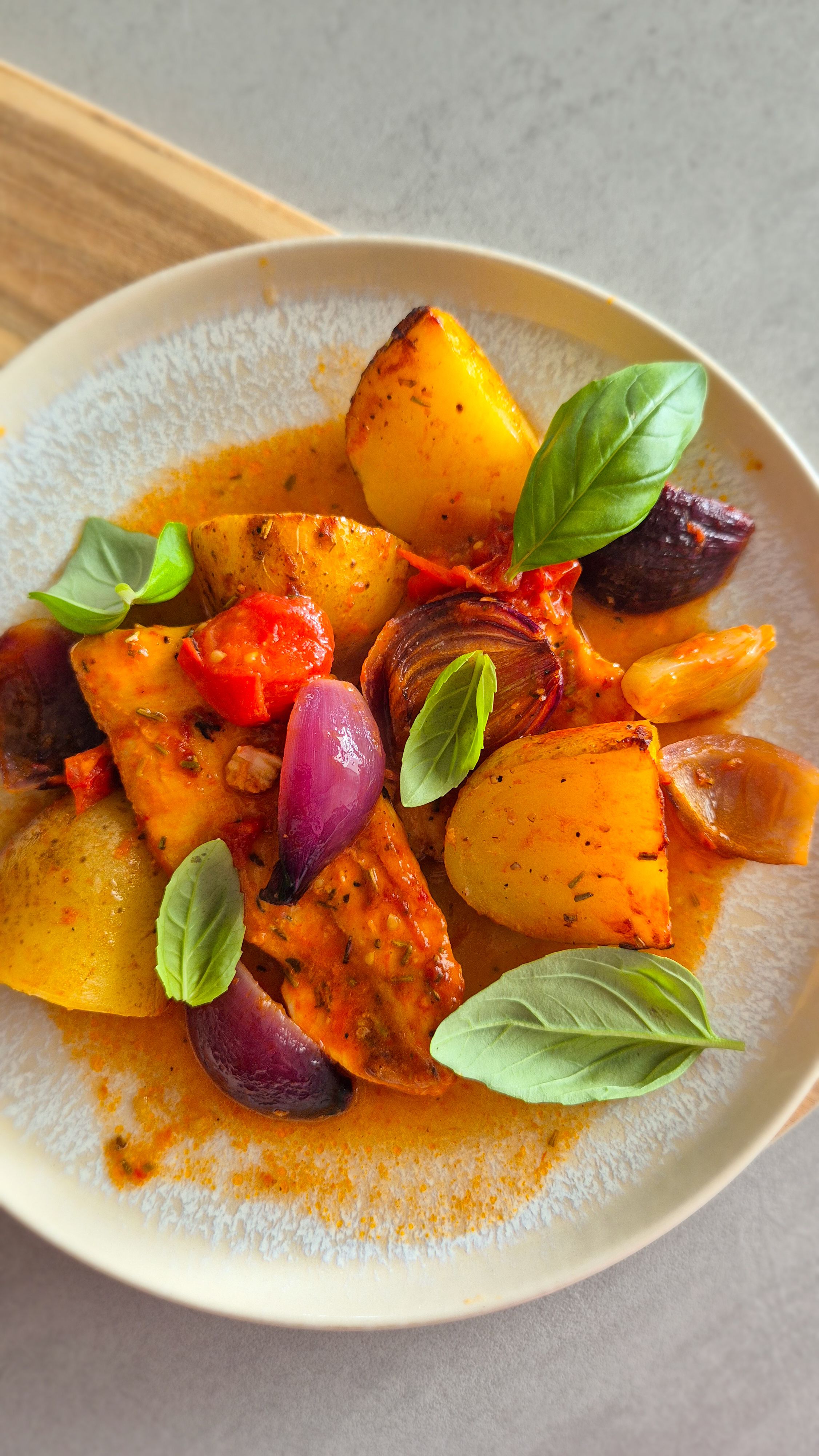 Einfaches Blechgericht mit Hähnchenbrust, Kartoffeln und Tomaten auf einem Teller serviert.
