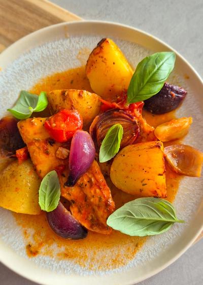Einfaches Blechgericht mit Hähnchenbrust, Kartoffeln und Tomaten auf einem Teller serviert.