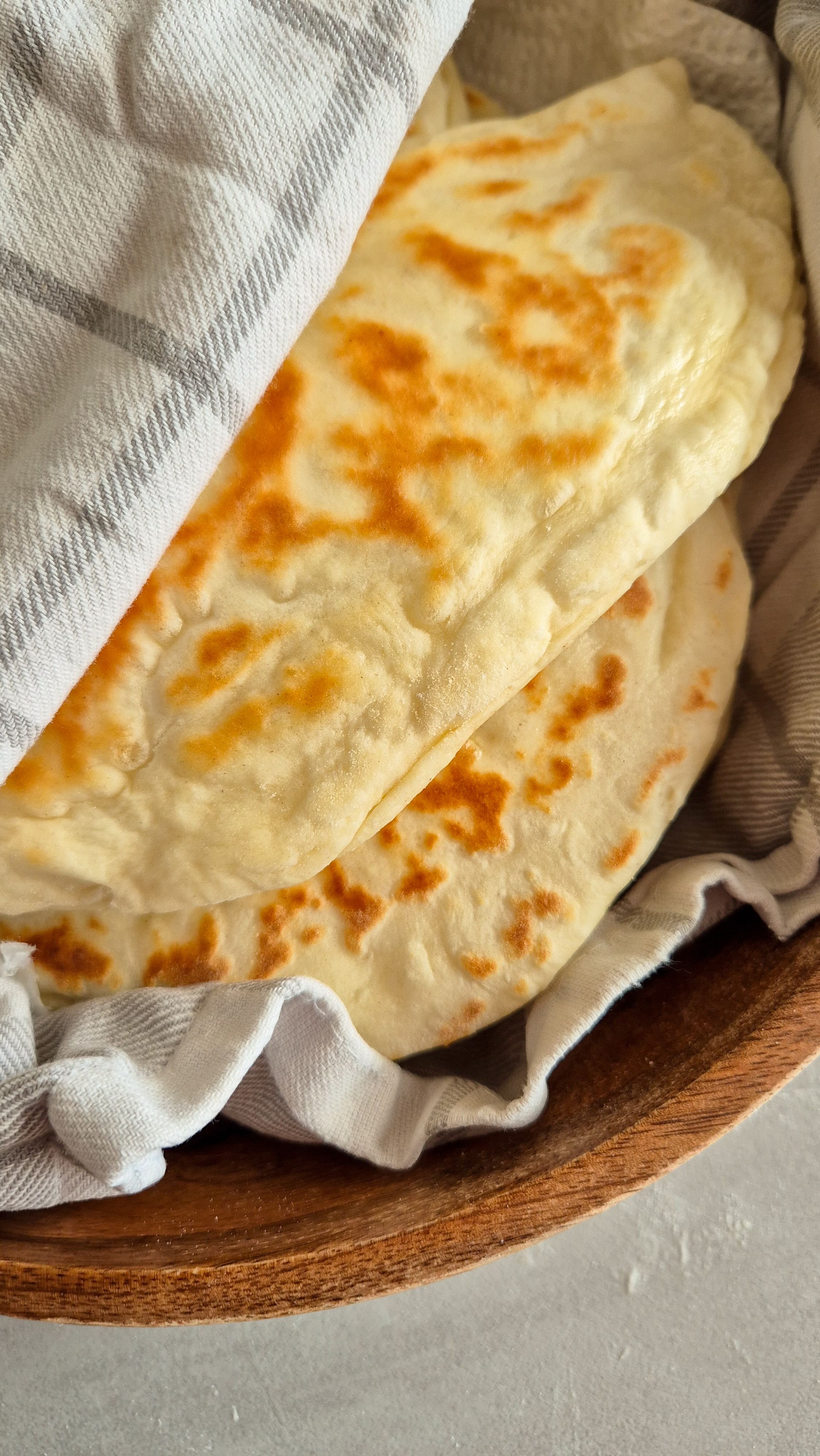 Teigtaschen mit einer Kartoffel-Käse-Füllung in einem Tuch gewickelt in einer Holzschale serviert.