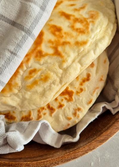 Teigtaschen mit einer Kartoffel-Käse-Füllung in einem Tuch gewickelt in einer Holzschale serviert.