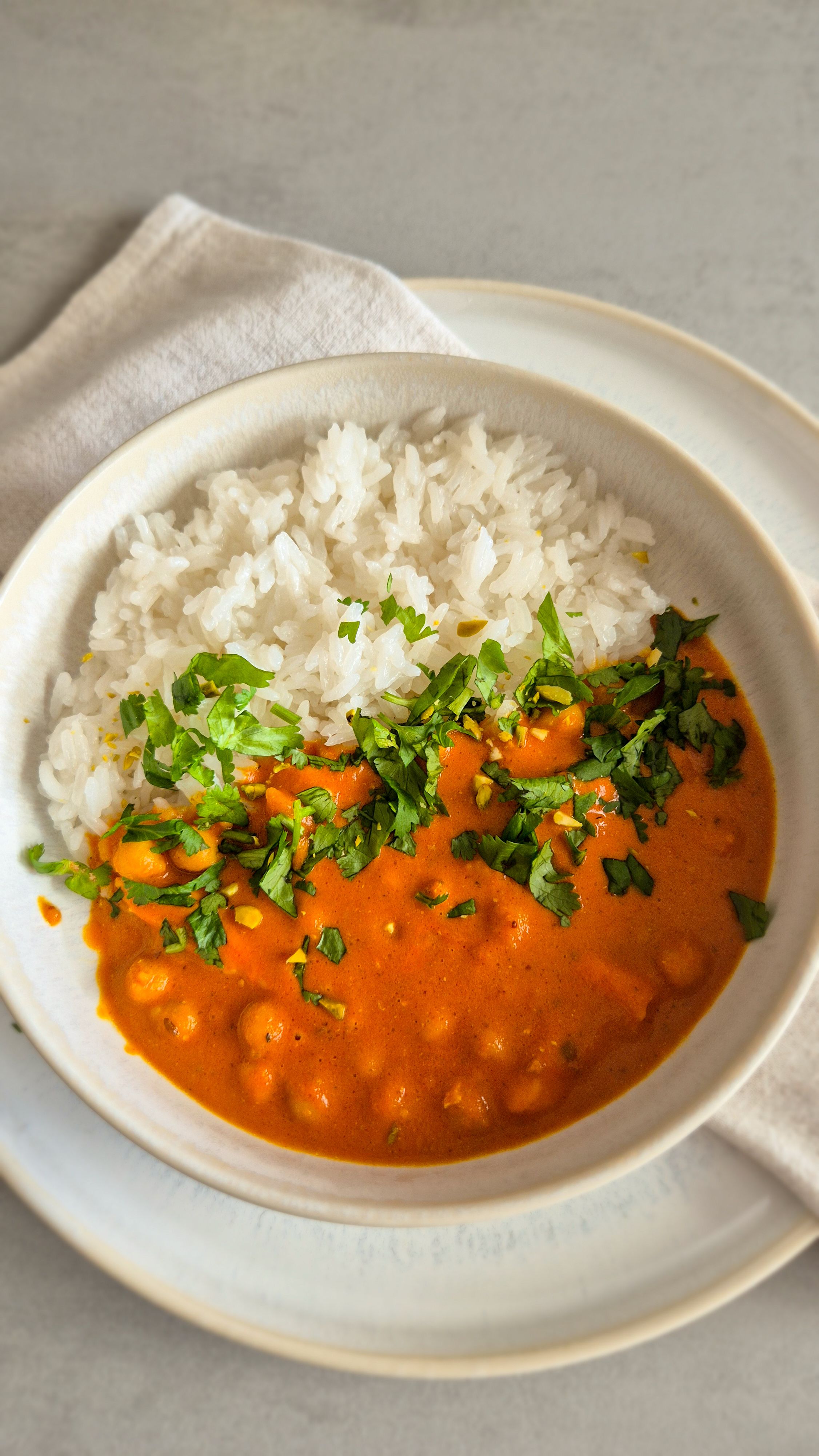 hausgemachtes, würziges Curry mit Kichererbsen nach nordindischer Art in einer Schale mit Koriander serviert.