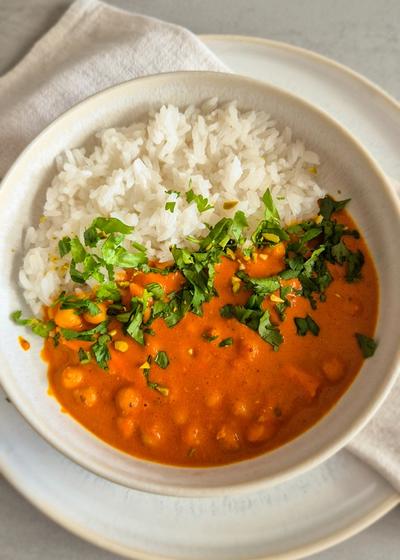 hausgemachtes, würziges Curry mit Kichererbsen nach nordindischer Art in einer Schale mit Koriander serviert.