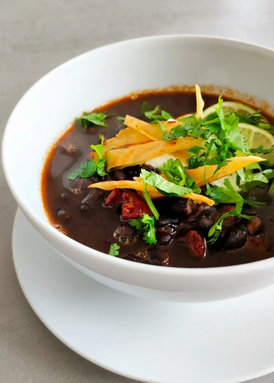 Schwarze Bohnensuppe aus Mittelamerika mit frischem Koriander und Totopos.