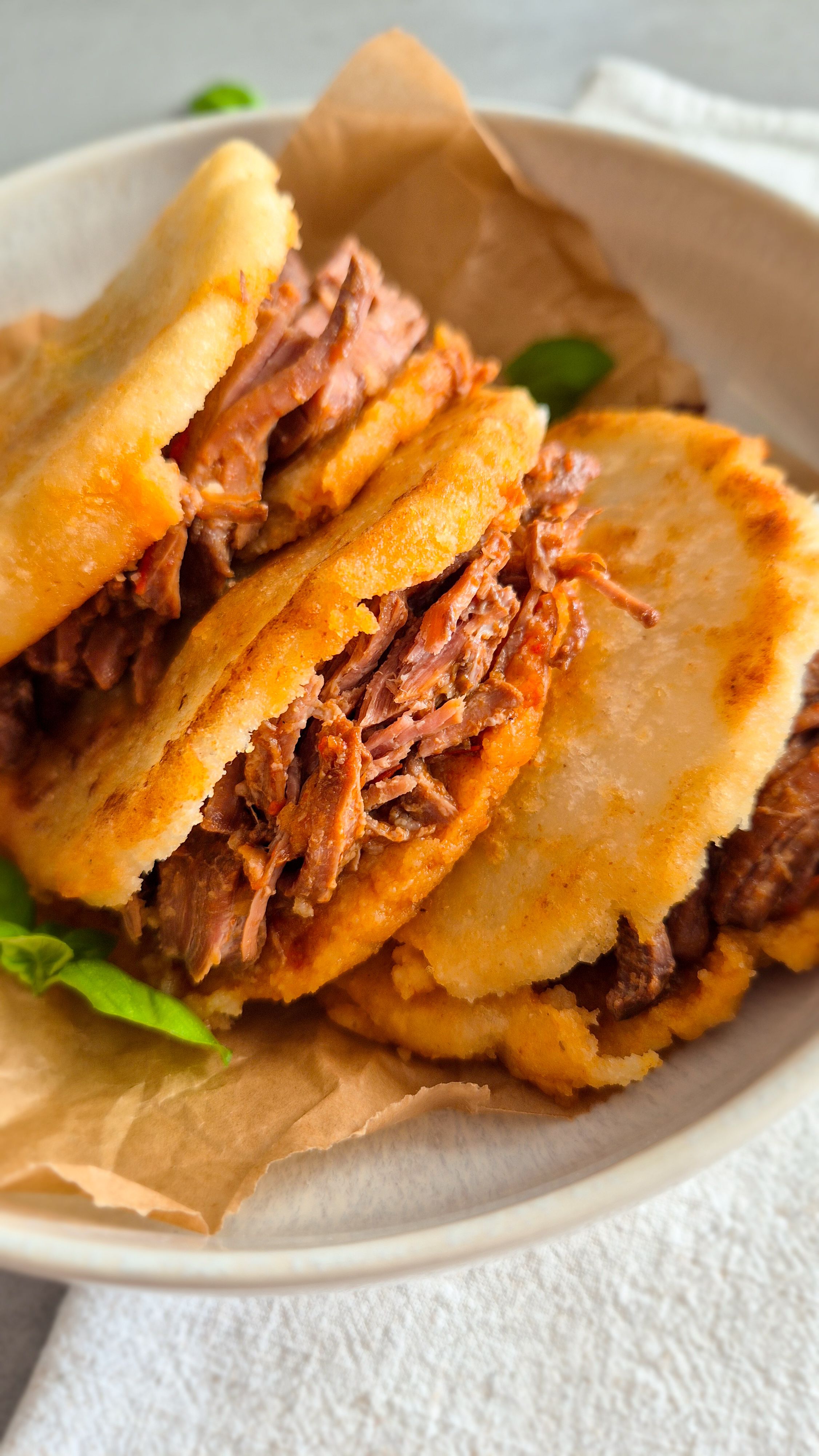 Venezolanische Arepas aus P.A.N. Maismehl mit Carne Mechada auf einem Teller.