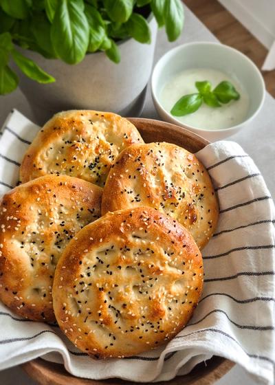Authentisches türkisches Fladenbrot mit Sesam und Schwarzkümmel in einer Schale mit einem Tuch umwickelt.