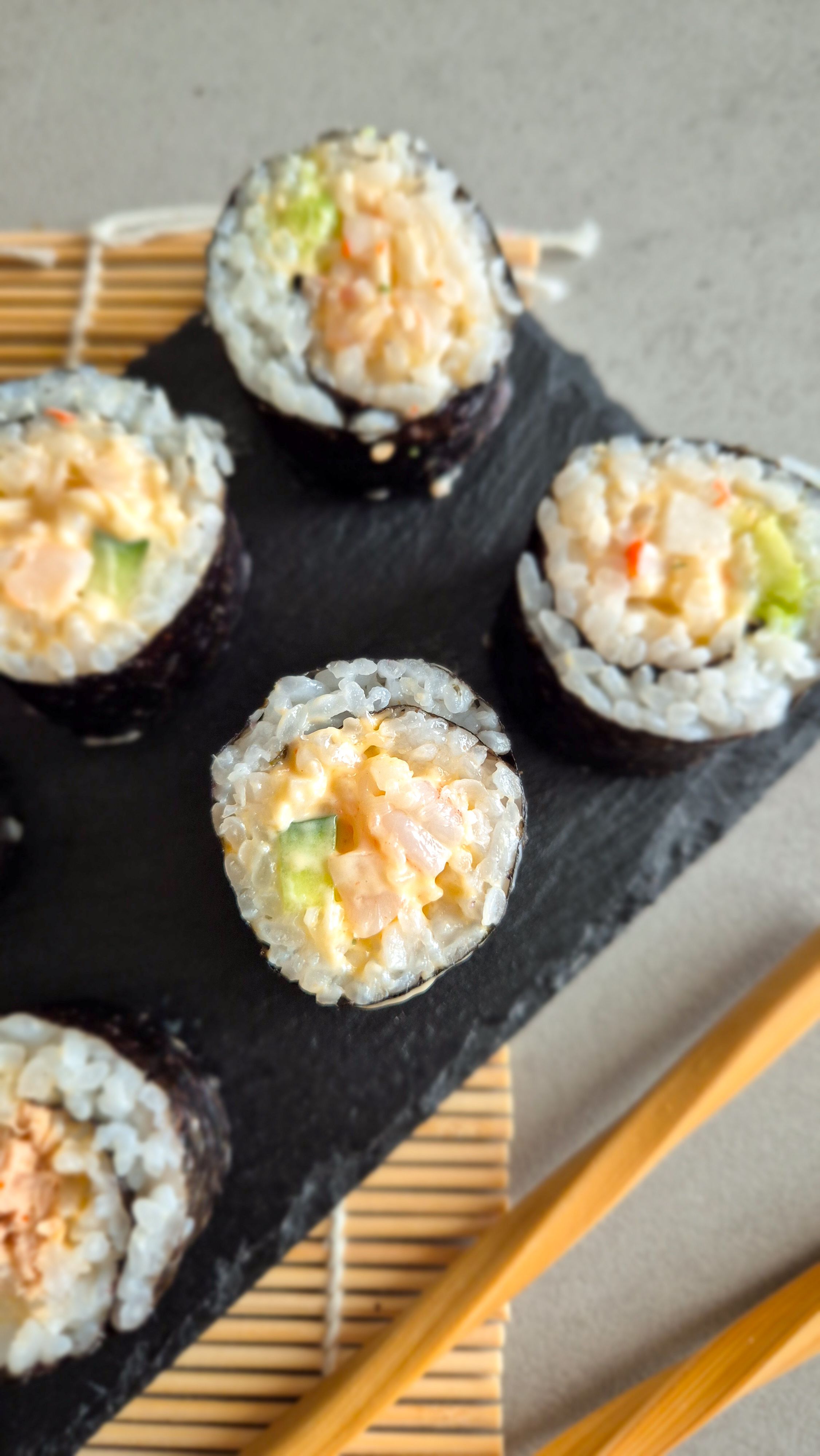 Spicy Surimi und Garnelen Sushi auf einer Schieferplatte serviert.
