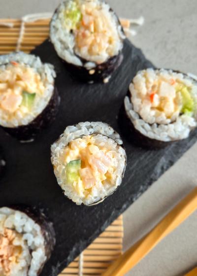 Spicy Surimi und Garnelen Sushi auf einer Schieferplatte serviert.