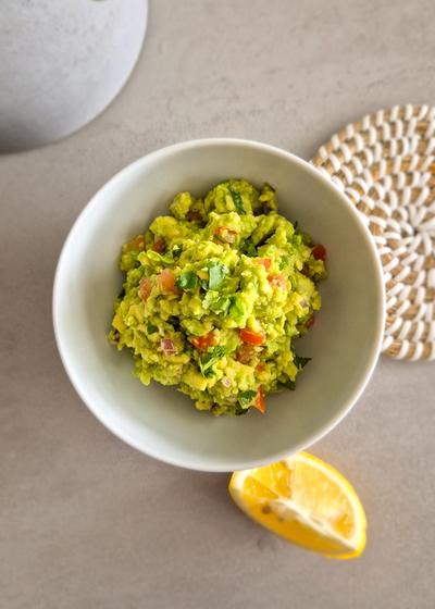 Eine frische Guacamole in einer Schale mit einer Limette.