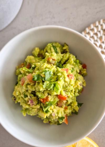Eine frische Guacamole in einer Schale mit einer Limette.
