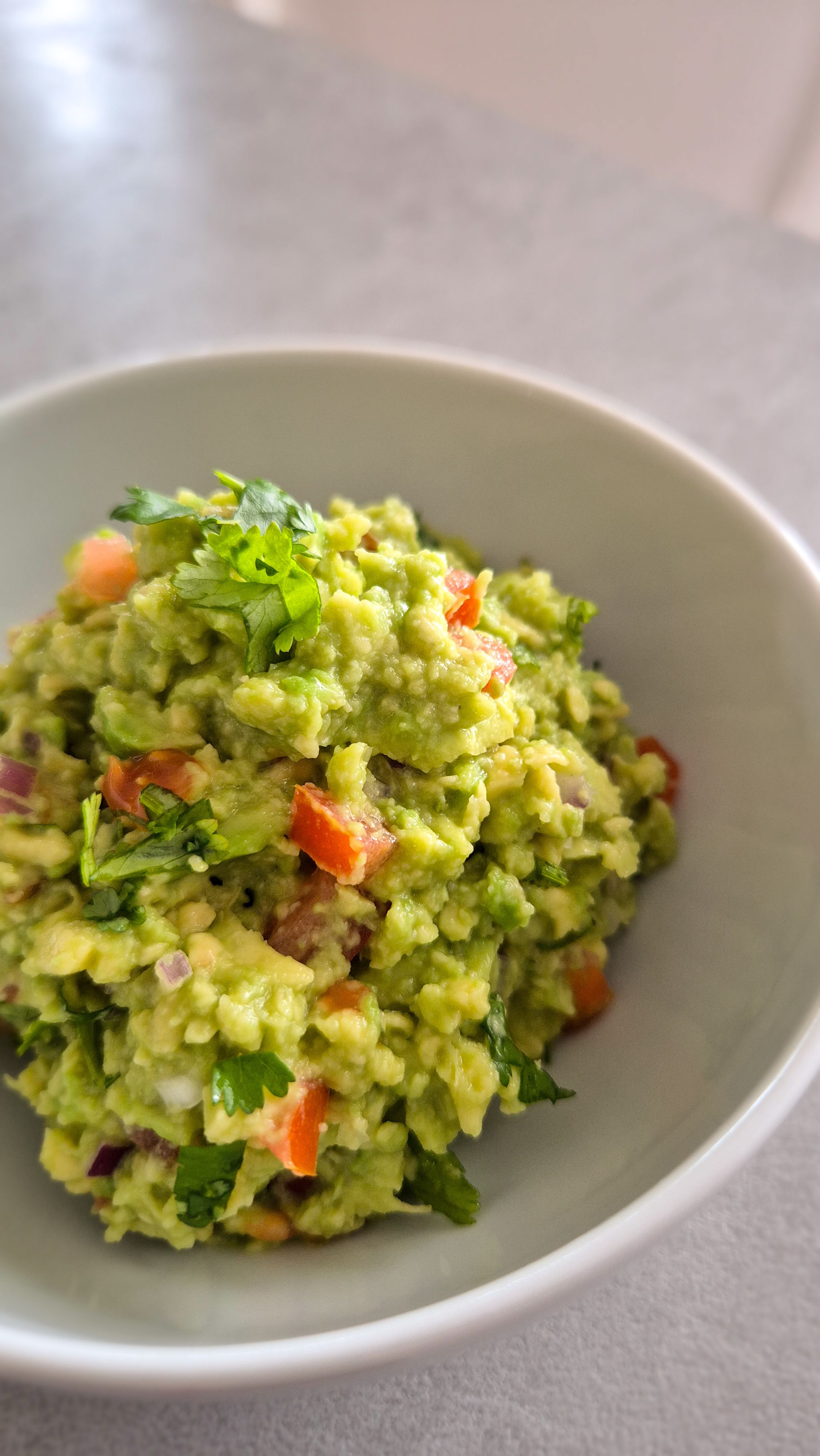 Eine frische Guacamole in einer Schale mit einer Limette.