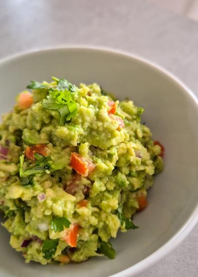 Eine frische Guacamole in einer Schale mit einer Limette.