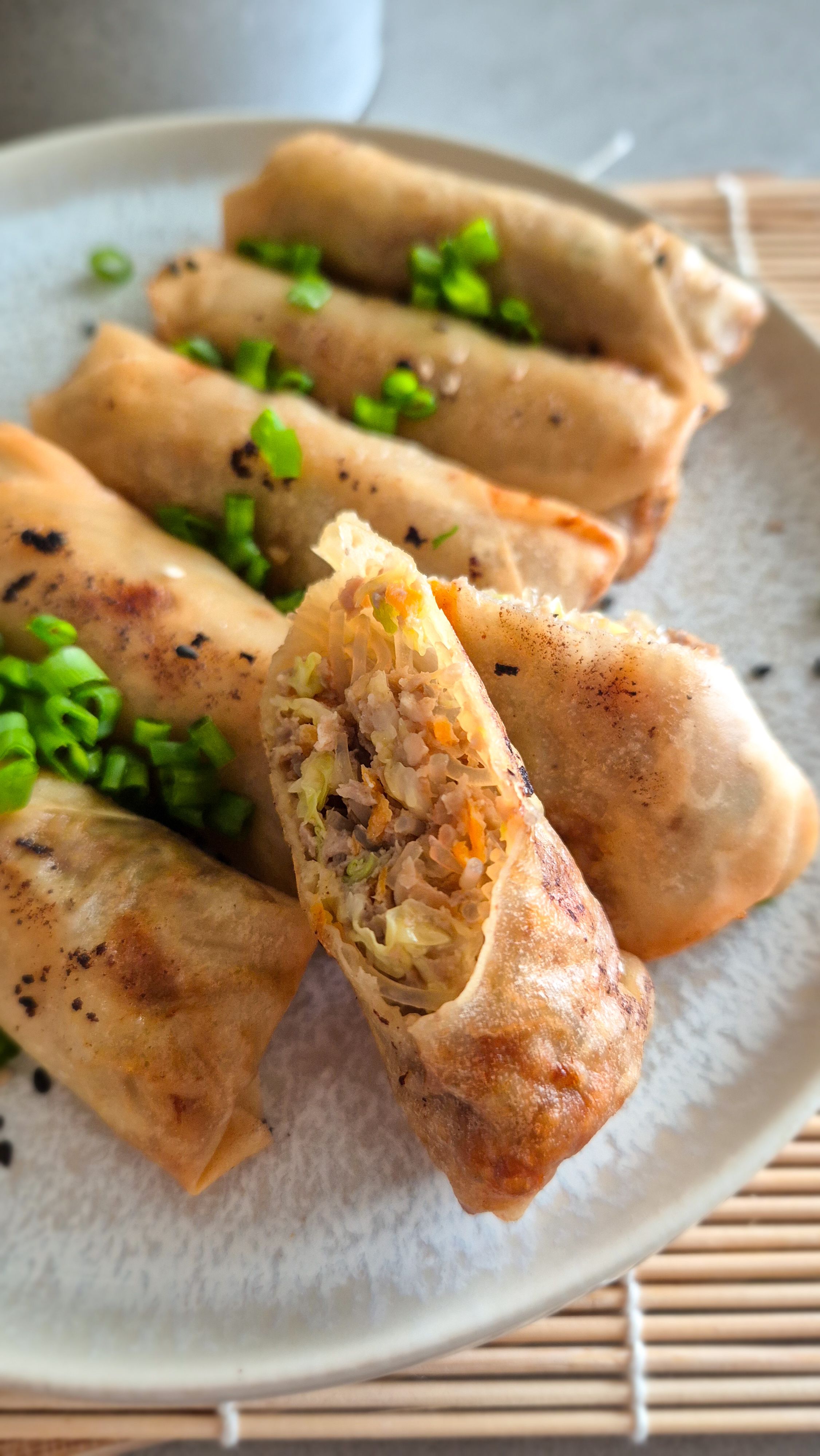 Chinesische Frühlingsrollen, nach original chinesischem Rezept, halbiert auf einem Teller serviert.