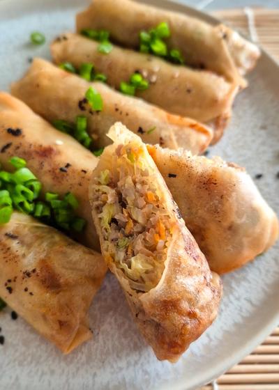 Chinesische Frühlingsrollen, nach original chinesischem Rezept, halbiert auf einem Teller serviert.