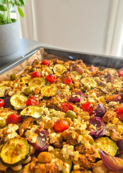 Griechisches Gemüse mit Hähnchen auf einem Blech.