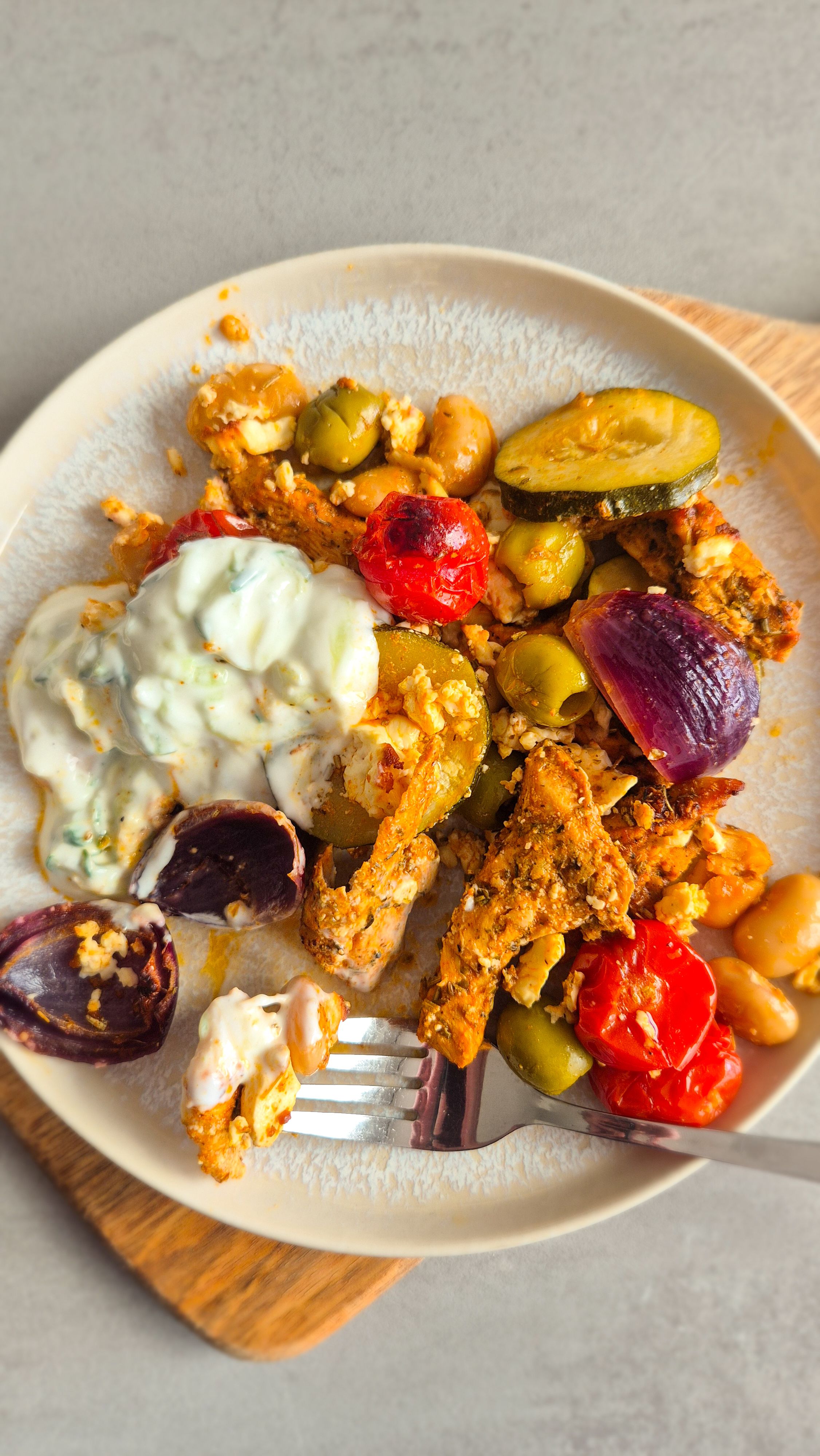 Blechgericht: Gemüse mit Hähnchen vom Blech nach griechischer Art mit Tzatziki auf einem Teller.