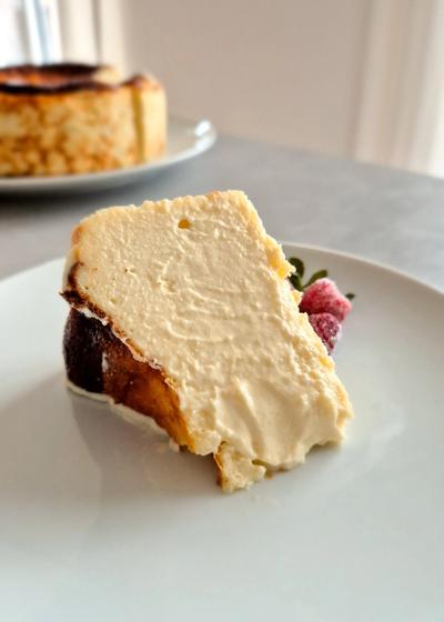 Ein Stück cremiger San Sebastian Cheesecake mit einer dunkelbraun karamellisierten Kruste auf einem Teller.