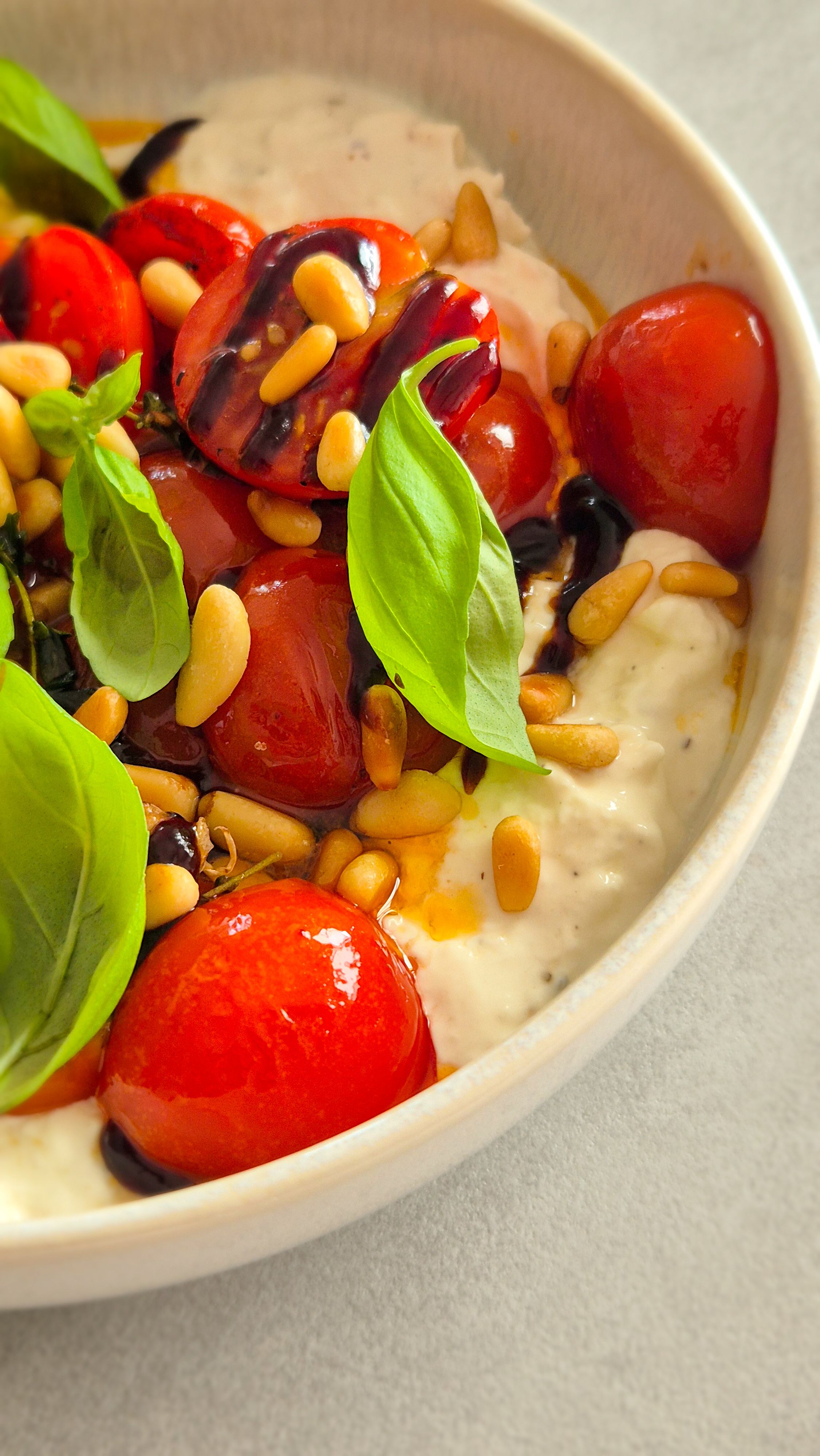 Cremiger Burrata Dip mit gerösteten Honig-Tomaten und Pinienkernen in einer Schale.