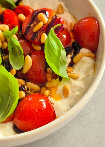 Cremiger Burrata Dip mit gerösteten Honig-Tomaten und Pinienkernen in einer Schale.