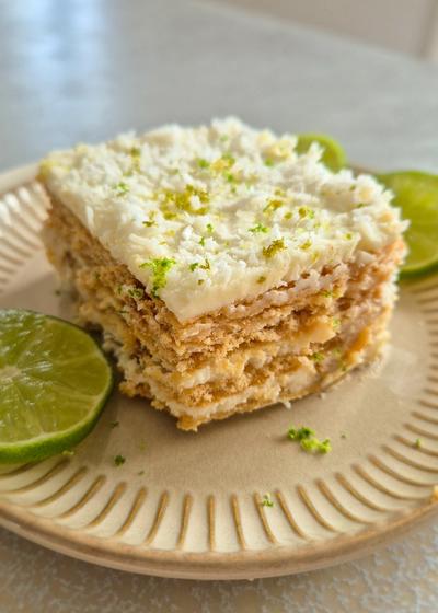 Ein Stück Carlota de Limón (mexikanischer Limettenkuchen) auf einem beigen Teller mit Limettenscheiben serviert.