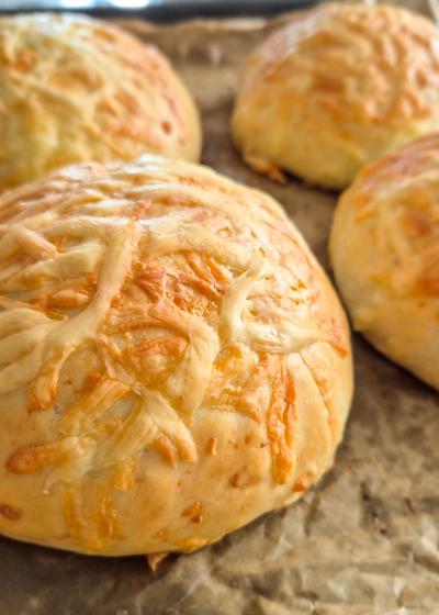 Selbstgebackene weiche Käsebrötchen frisch aus dem Ofen auf einem Blech.