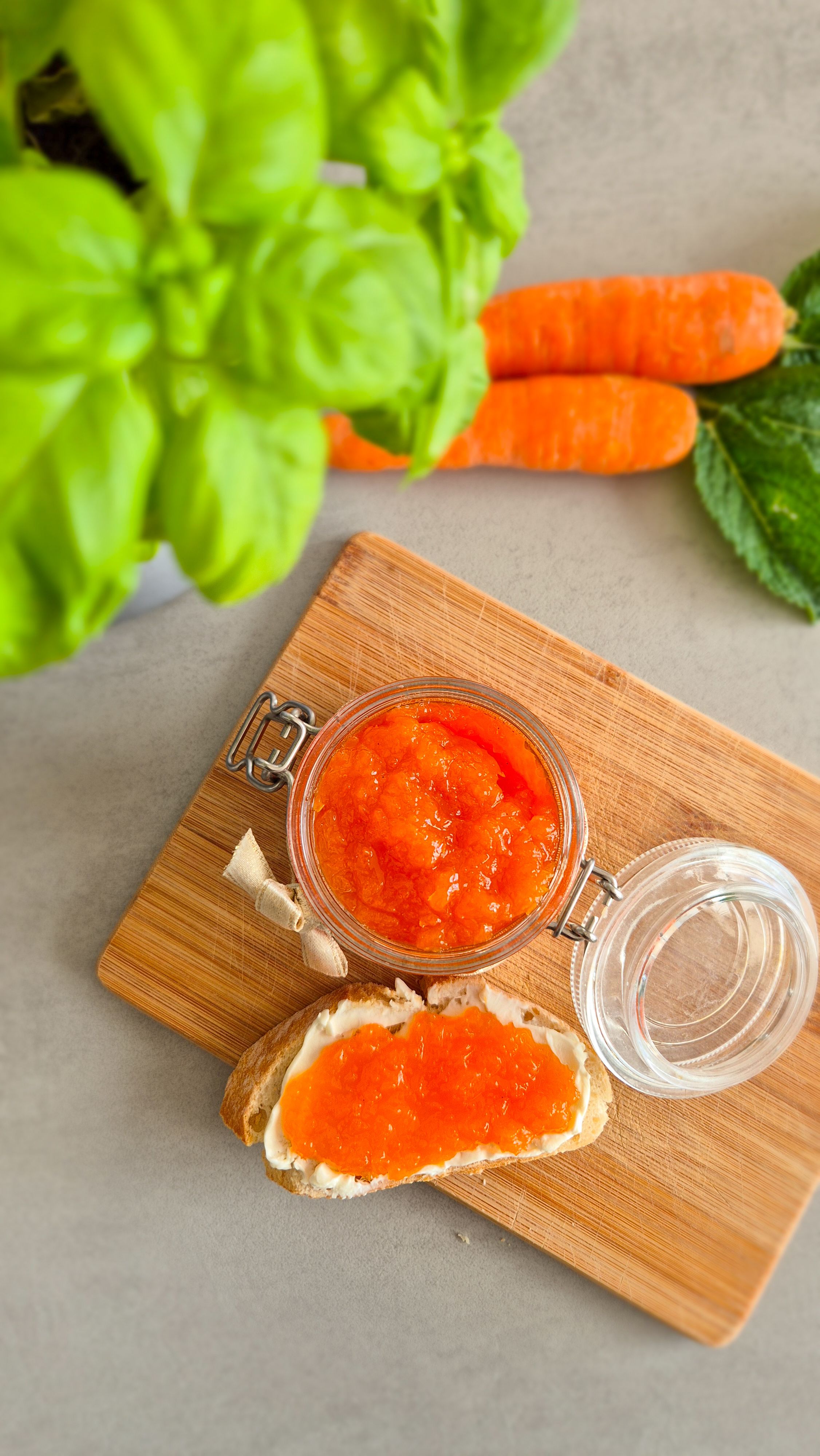 Ein dekorativ angerichtetes Glas Hasenfrühstück (Karotten-Apfel-Marmelade) mit einem Baguette zum Frühstück.