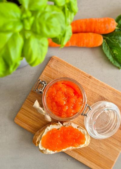 Ein dekorativ angerichtetes Glas Hasenfrühstück (Karotten-Apfel-Marmelade) mit einem Baguette zum Frühstück.