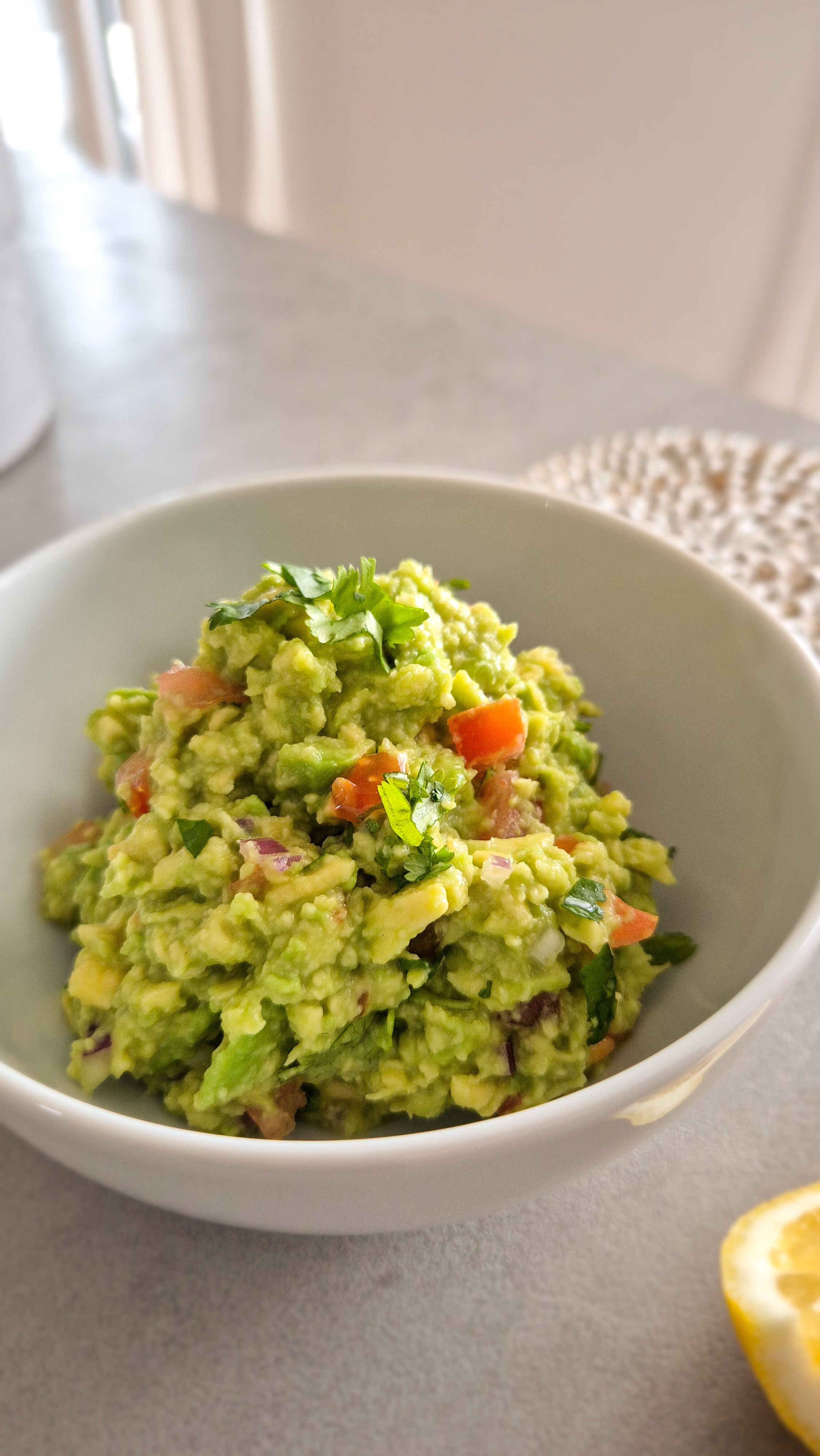 Eine frische Guacamole in einer Schale mit einer Limette.