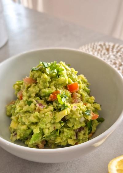 Eine frische Guacamole in einer Schale mit einer Limette.