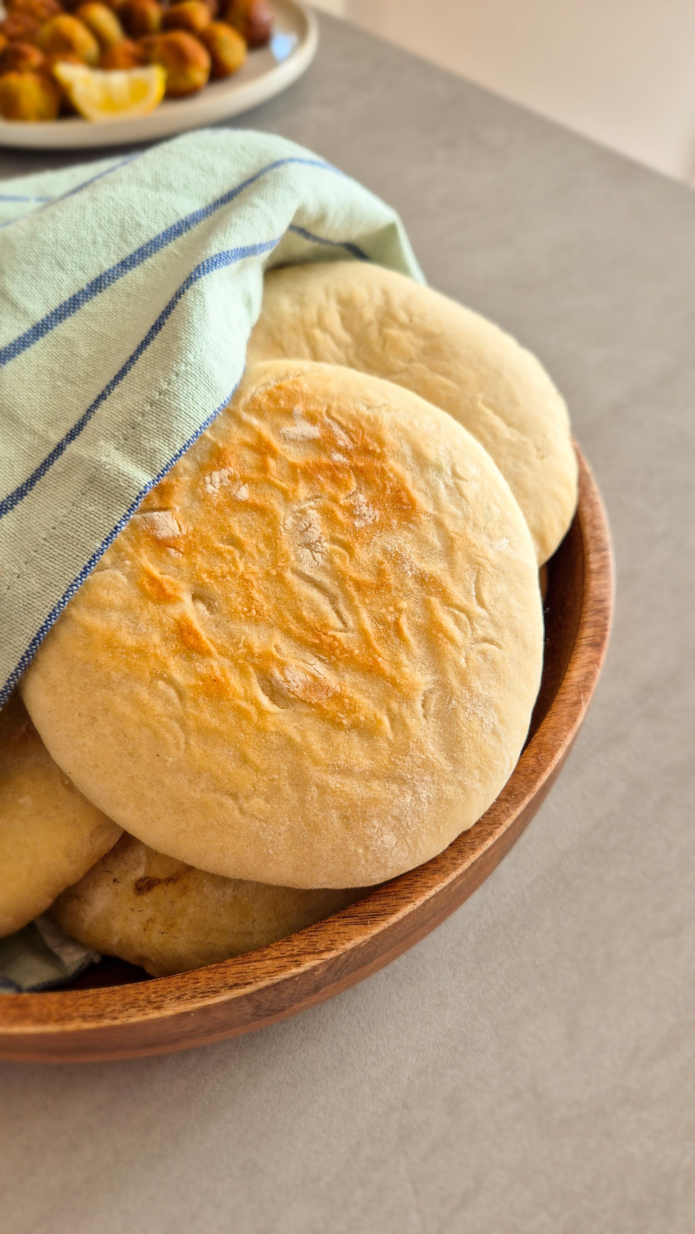 Fluffiges Pita-Brot in einer Holzschale mit einem Tuch umwickelt.