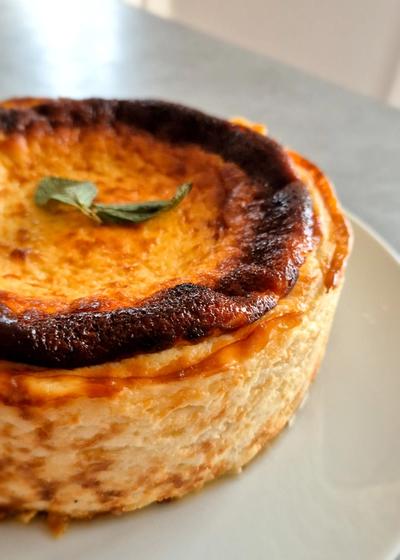 Rustikaler San Sebastian Cheesecake mit einer dunkelbraun karamellisierten Kruste und cremigen Kern auf einem Teller.